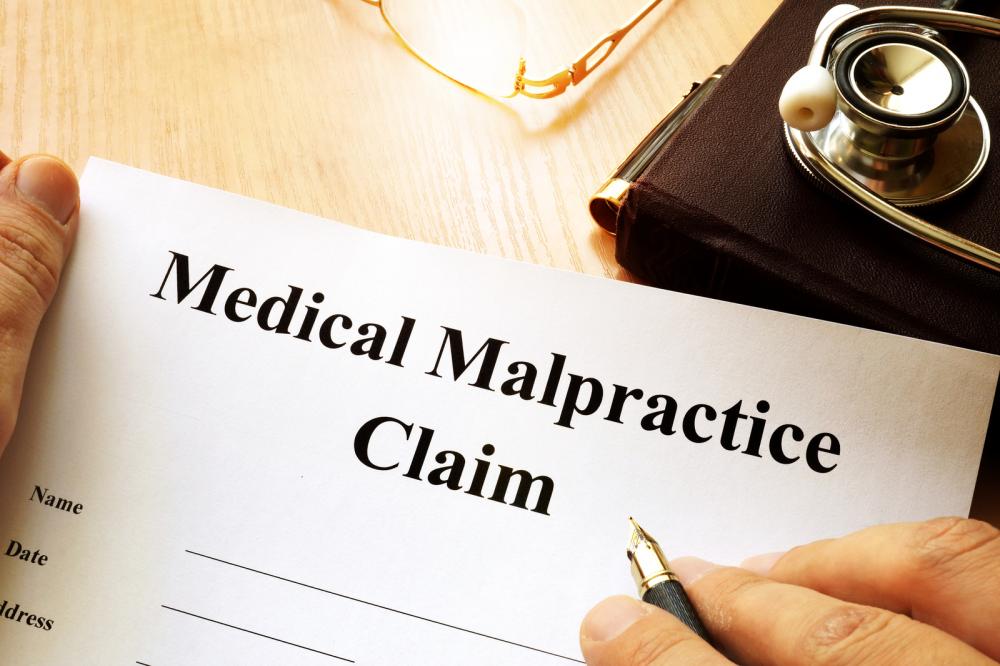 A close-up of a person filling out a medical malpractice claim form.