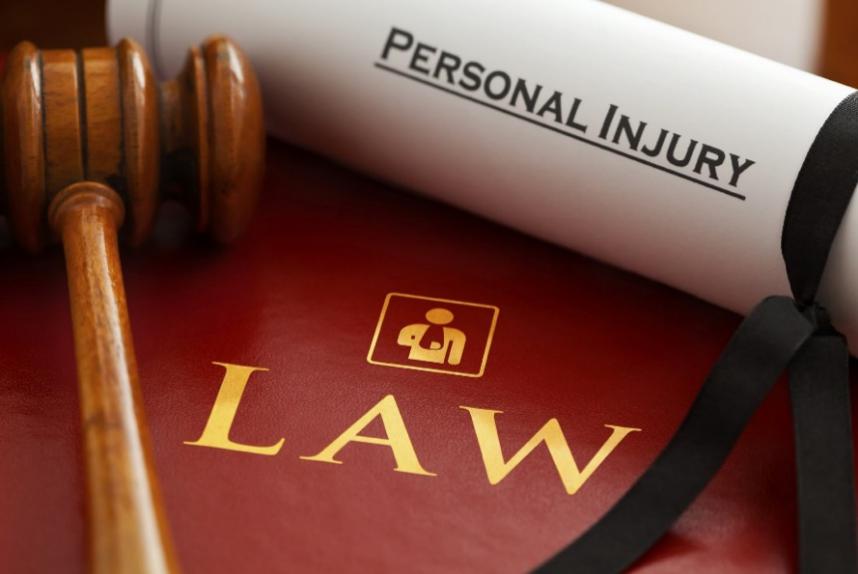 A paper with “Personal Injury” written on it next to a gavel and on top of a book with “Law” written on it